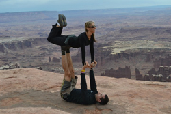 couple doing yoga at the tip of a mountain